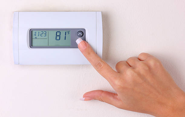 istock thermostat. woman's hand setting the wall heater 519665711