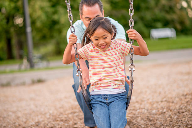 istock A father is pushing her daughter on the swing. They 519676822
