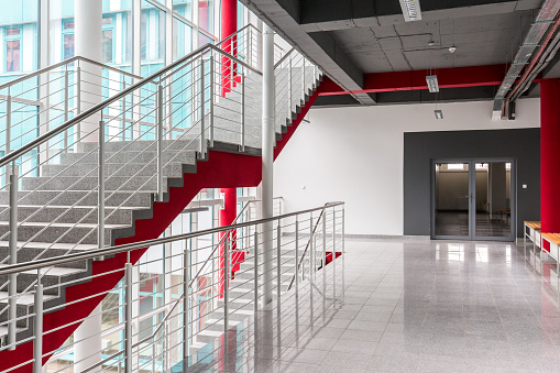 Modern, light staircase with silver railing, red details and black ceiling