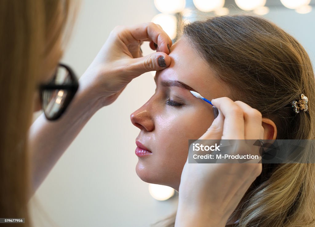 Make-up artist cleaning skin on model's face. Adult Stock Photo