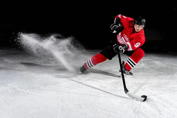 Ice hockey player shooting puck in ice hockey stadium.