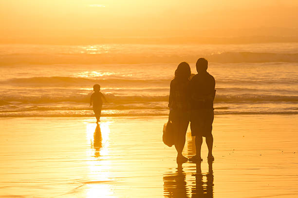 istock Parents watching kid silhouettes at sunset on beach 519681509