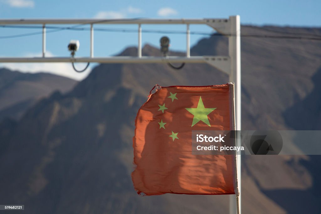 Red Flag of China in the wind with defocussed cameras Flag of China in the wind with defocussed security cameras in the background on the Friendship highway in Tibet Chinese Culture Stock Photo