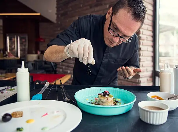 Photo of Portrait of chef arranging plate of food