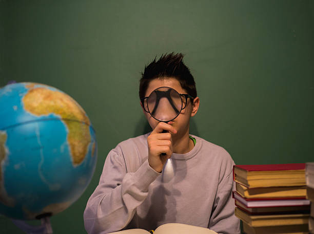 istock Boy amazed looking through a magnifying glass 519682508