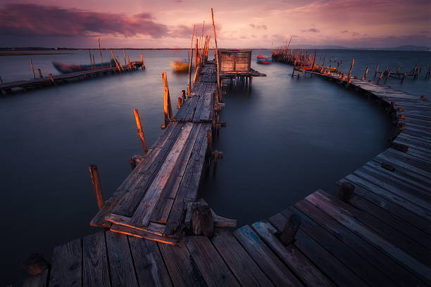 SUNRISE IN CARRASQUEIRA The Palafitos de Carrasqueira are a unique site at the mouth of the Sado River in Portugal. They are characterized by being a wooden jetty that at high tide become a dream place for every person who loves the landscape. Its boats, huts and clouds, become an almost magical place.  Sado stock pictures, royalty-free photos & images