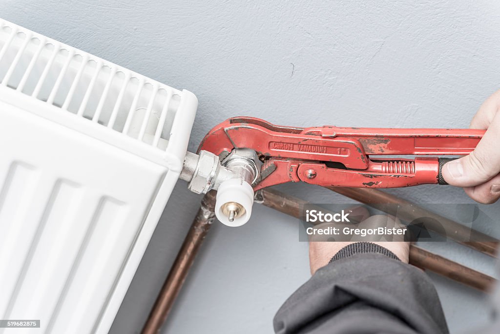 Man fixing radiator Man fixes broken radiator Adjustable Stock Photo