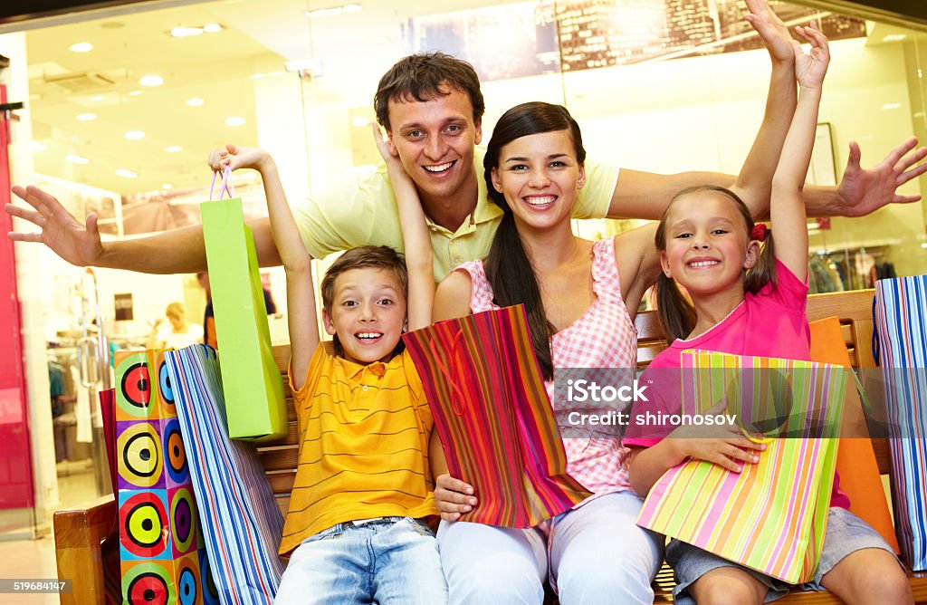 After shopping Portrait of joyful family sitting in store with plenty of shopping bags Adult Stock Photo