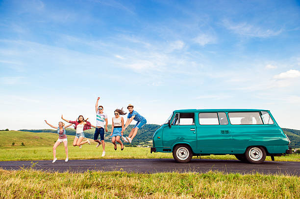 Jumping frieds with campervan, green nature and blue sky Young teenage hipster frieds with campervan against green nature and blue sky, jumping hopper car stock pictures, royalty-free photos & images