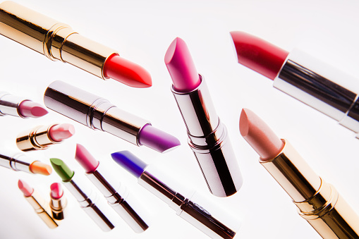 Different-colored flying lipsticks on white background