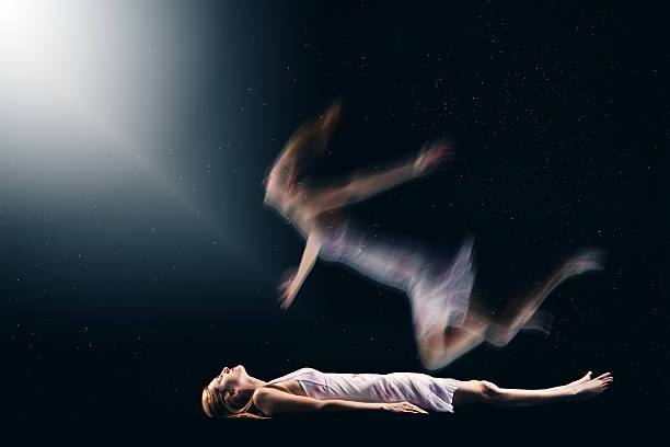 Woman Having Spiritual Out Of Body Experience A concept image of a woman's spirit drifting from her body and floating towards a light. levitation stock pictures, royalty-free photos & images