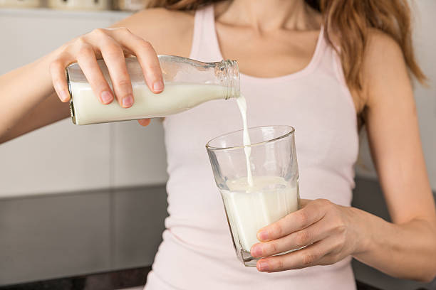 frau gießen milch aus der flasche - cows milk fotos stock-fotos und bilder