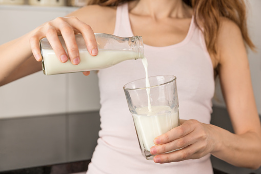 Woman pouring milk into a glass.