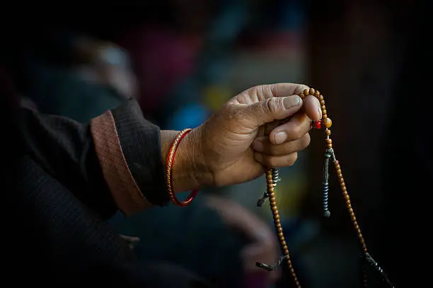 Hands of a Tibetan Buddhist cycles through his prayer beads while chanting.