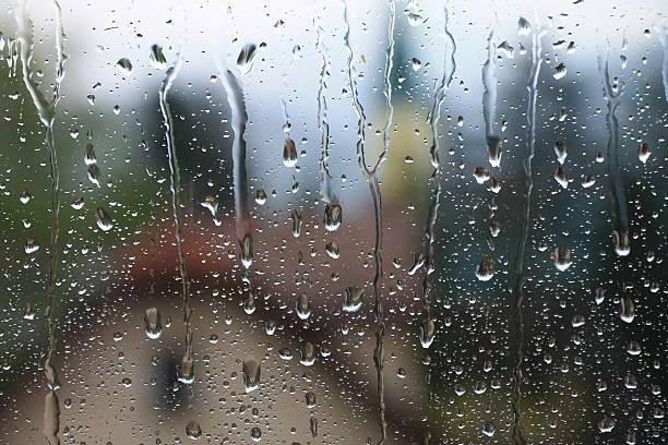 istock Rain drops on window with house and church in background 519688408