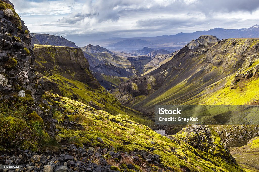 Moss covered valley on Fimmvorduhals, Thorsmork in the distant. Hiking on Fimmvorduhals, looking through a valley with moss covered mountain sides, Thorsmork visible in the distant. Iceland Stock Photo
