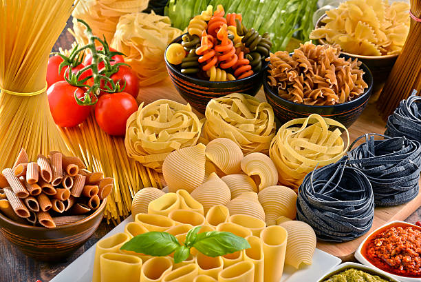 Plate of cooked italian pasta, penne rigate on fork with tomatoes and basil leaves