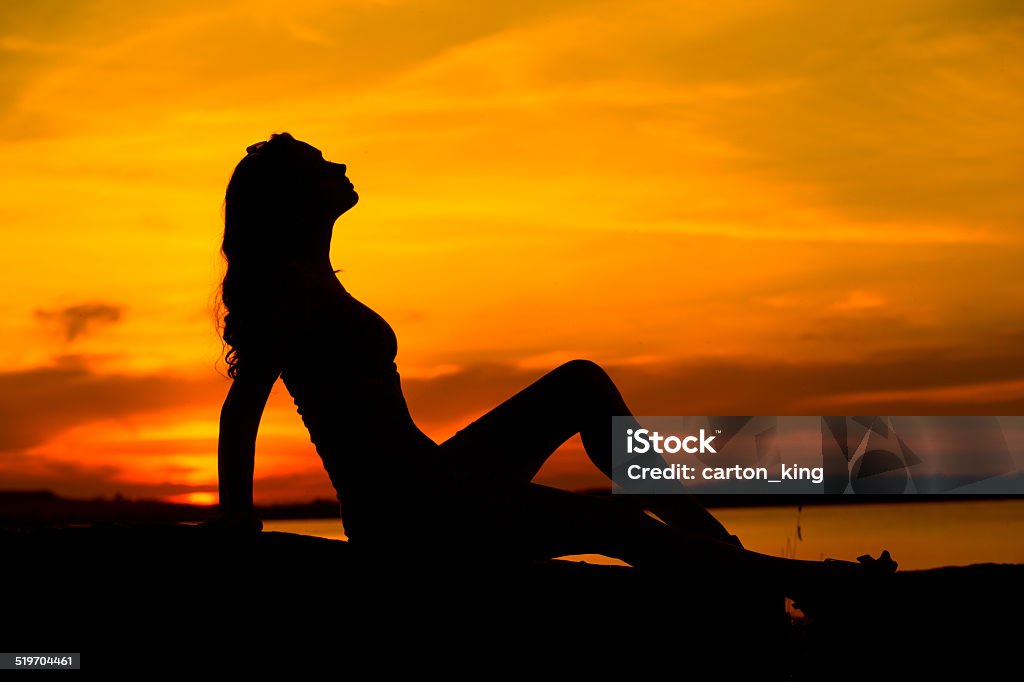 Silhouette of pregnant woman sitting on the sand Silhouette of the pregnant lady sitting on the sand Abdomen Stock Photo