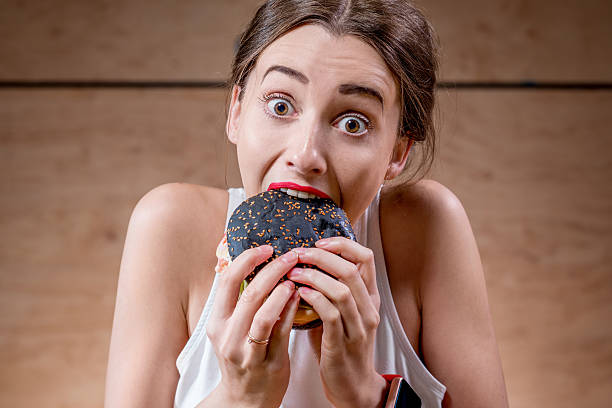 istock Woman eating black burger 519705416