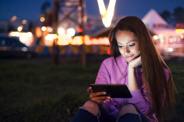若い女性デジタルタブレット外を使用して、アミューズメントパーク - ferris wheel luna park amusement park carnival ストックフォトと画像