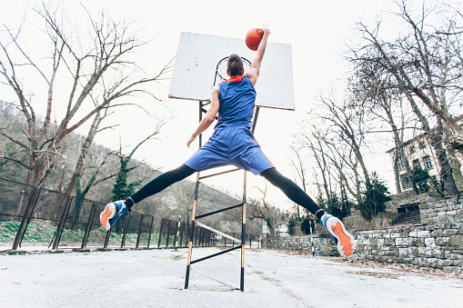 Young man jumping to score a slam dunk in basketball