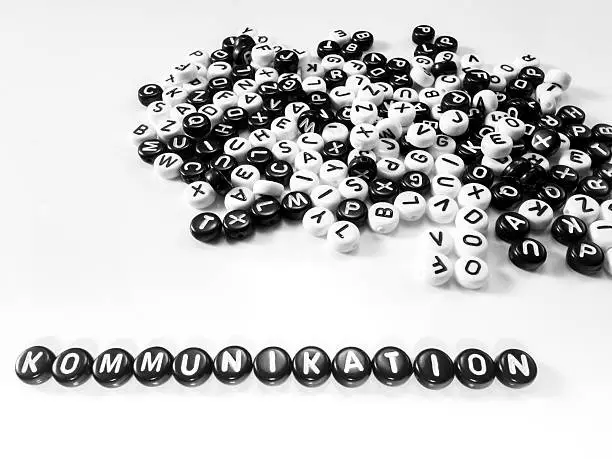 heap of round letters black and white and communication word written in german written by side; kommunikation