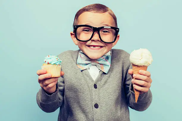 Photo of Young Nerd Boy Holds Ice Cream and Cupcakes