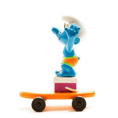 Fosston, USA - April 5, 2016: A vintage Smurf character on an orange skateboard.  The Smurfs, an American- Belgian animated fantasy-comedy is centered on fictional little blue creatures that live in mushroom houses in an enchanted forest.  They live a carefree life, except for one major threat - Gargamel, an evil wizard and his feline companion Azrael.  The Smurfs television series aired on NBC from September 12, 1981 to December 2,1989.