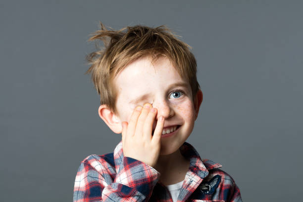 istock smiling red-hair child hiding one eye for fun eyesight 519715952