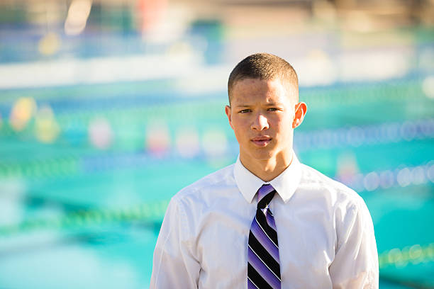 High School Senior Photo Senior photo portrait of a water polo athlete at an outdoor pool wearing formal clothes with a tie. high school photos stock pictures, royalty-free photos & images