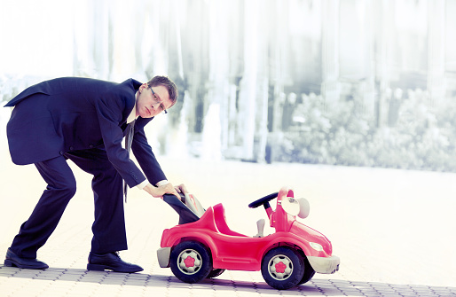 Businessman Contemplating a Red Toy Car and Thinking about Next Business Move