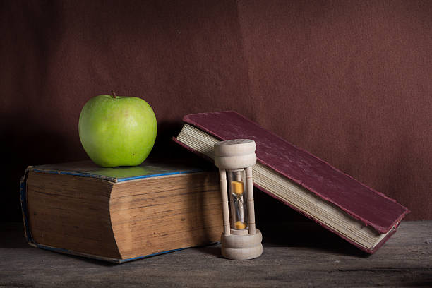 istock Still life green apple with books and hourglass. 519721395