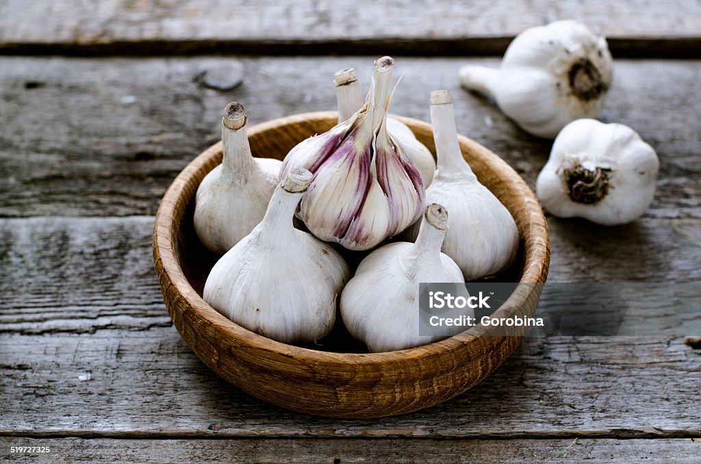 garlic in a bowl on the wooden table Organic garlic in a wooden bowl on the wooden table Close-up Stock Photo