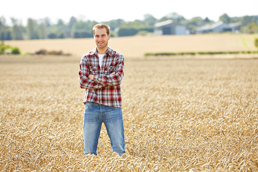 Proud farmer with folded arm standing in field