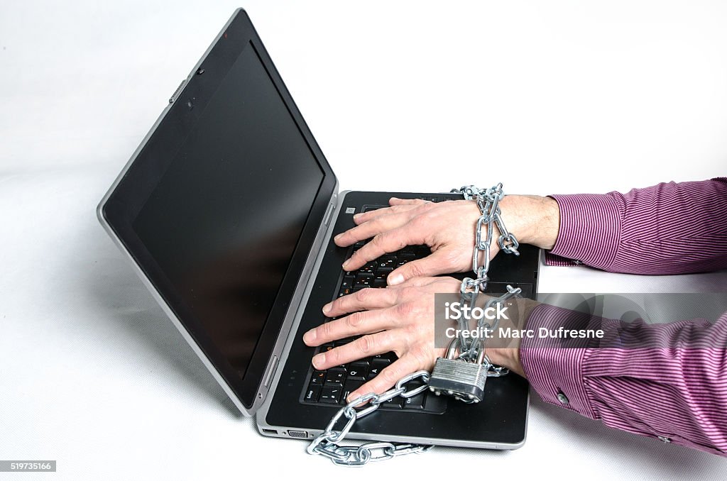 Laptop and hands locked with a chain and padlock Laptop and hands locked with a chain and padlock on white backgroug to simulate virus attack Accessibility Stock Photo