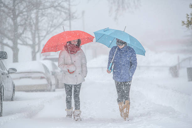 zwei teenager-mädchen mit regenschirm unter schneefall auf der straße - queens head stock-fotos und bilder