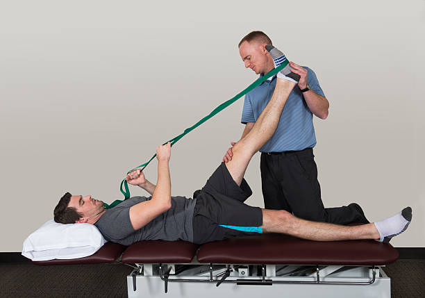 Leg Stretch With Strap in Physical Therapy Physical therapist stretching patient's hamstring and leg with use of a stretching strap. hamstring stock pictures, royalty-free photos & images