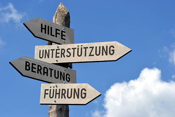Support signpost - in German Wooden singpost with "Help, support, advice, guidance" arrows against blue sky. crossroads sign stock pictures, royalty-free photos & images