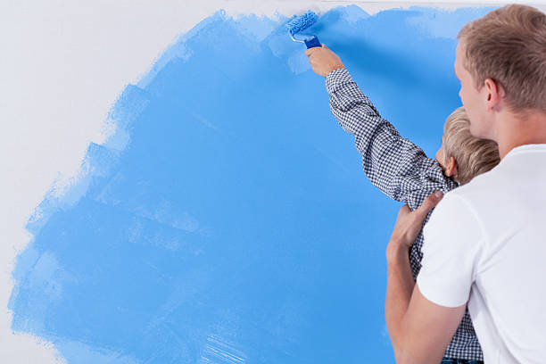 istock Father raising his son during painting the wall 519750367