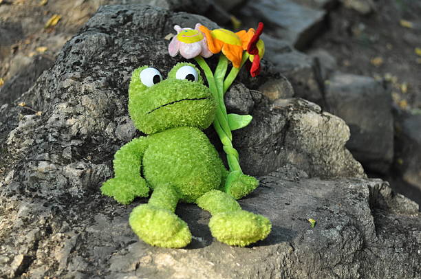 istock green toy frog on the nature sits on a rock 519752016