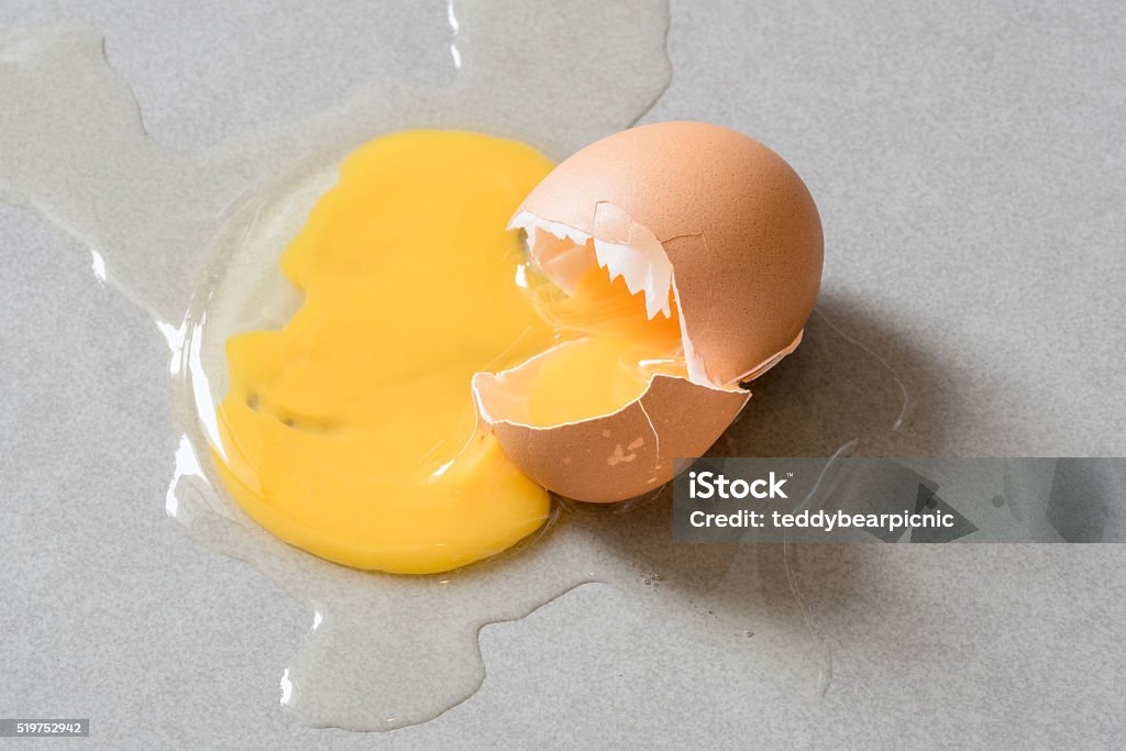 Egg drop crack splattered down on ceramic tile. Egg drop crack splattered down on ceramic tile. Abstract macro with shallow and depth of field effect Agriculture Stock Photo