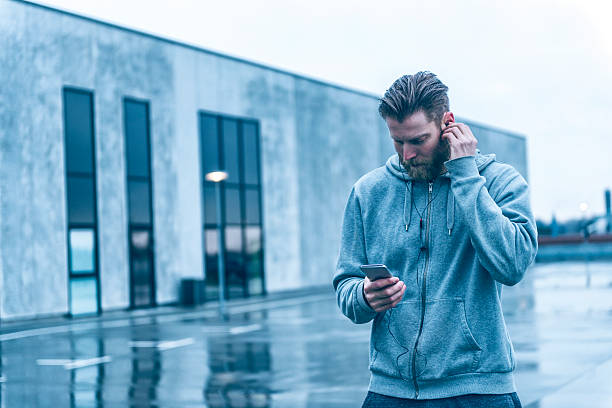 istock Man with beard listens to music on smart phone outside 519755346