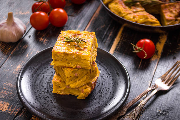 fetta di tortilla de patatas su un piatto nero - tortilla de patatas foto e immagini stock