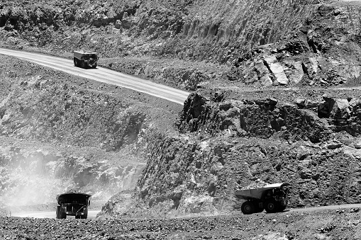 Loaded industrial trucks carrying heavy load of golden ore uphill from open pit gold mine in Kalgoorlie, Western Australia.