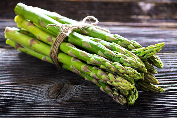 istock Bunch of fresh asparagus on wooden table 519760648