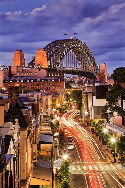 Sy Rocks Bridge Set Vert Vertical view over George street in the Rocks, Sydney, at sunset when bright lights illumnate the street , shops and people. george vi stock pictures, royalty-free photos & images