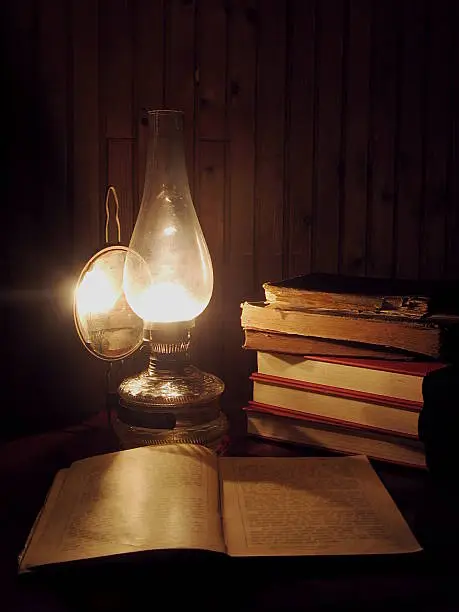 Old books lit by an oil lamp.