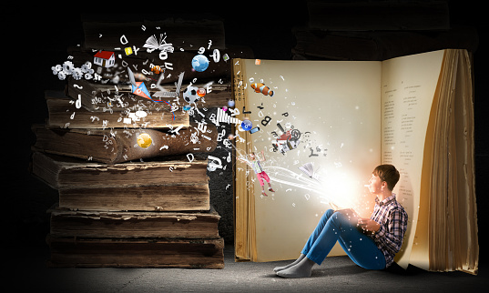 Teenager boy in jeans and shirt reading book