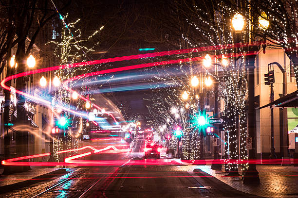 Morrison Steert in Portland, Oregon A long exposure of Morrsion St. in Portland, Oregon at night. There are light trails from cars and the MAX train. The trees have lights on them and the ground is reflecting light from the rain. morrison stock pictures, royalty-free photos & images