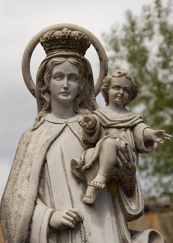 Marble figure of Madonna and Child aged with time in a cemetery